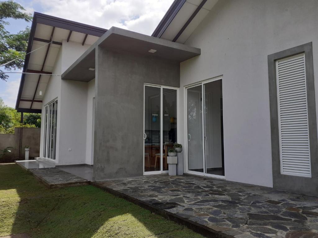 a white house with glass doors and a yard at Sathmani in Pallekele Kadawidiya
