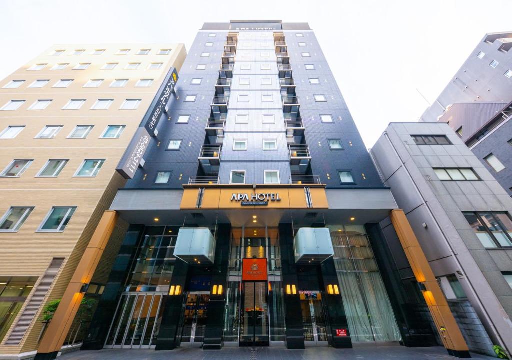 un edificio alto con un cartello davanti di APA Hotel Ningyocho Ekikita a Tokyo