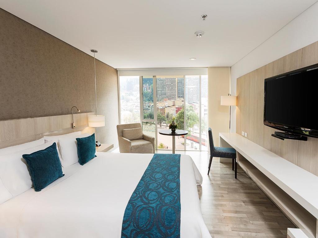 um quarto de hotel com uma cama e uma televisão de ecrã plano em Hotel bh Bicentenario em Bogotá