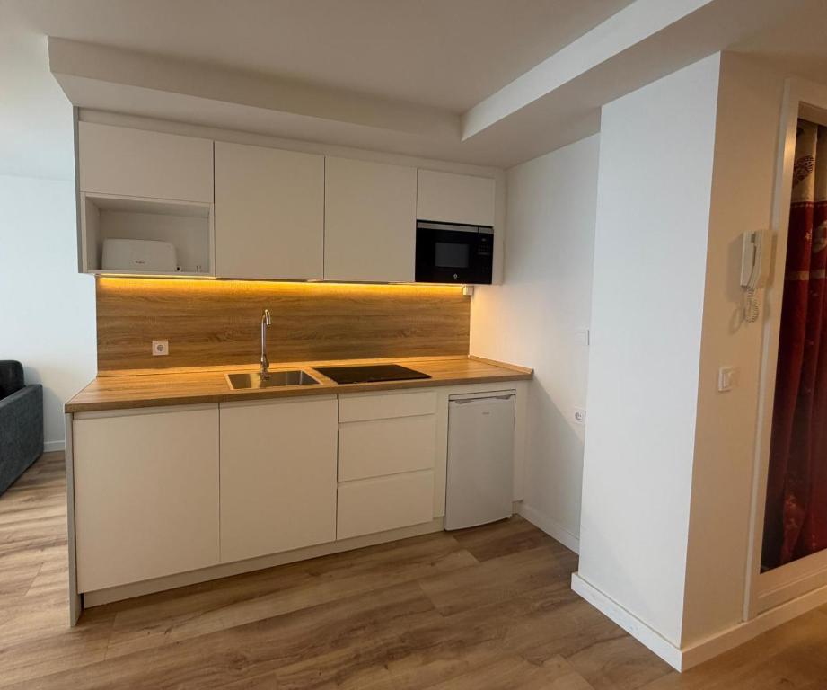 a kitchen with white cabinets and a sink at Apartamentos Pirineos Rent in Candanchú