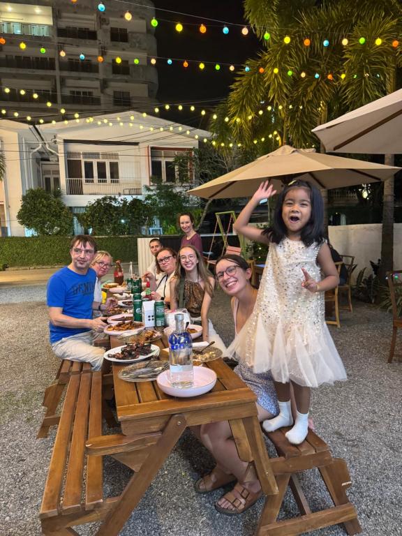 Een groep mensen zit aan een tafel met een klein meisje dat een paraplu vasthoudt. bij Colombo Mount Hostel in Mount Lavinia