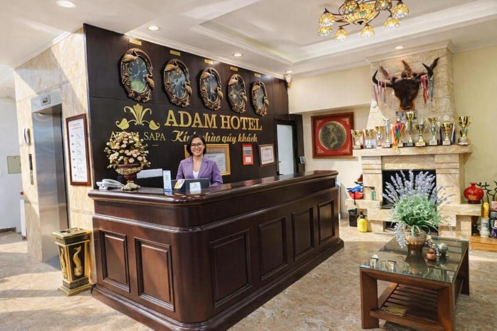 een vrouw staat achter een toonbank in een kamer bij Adam Hotel Sa Pa in Sa Pa