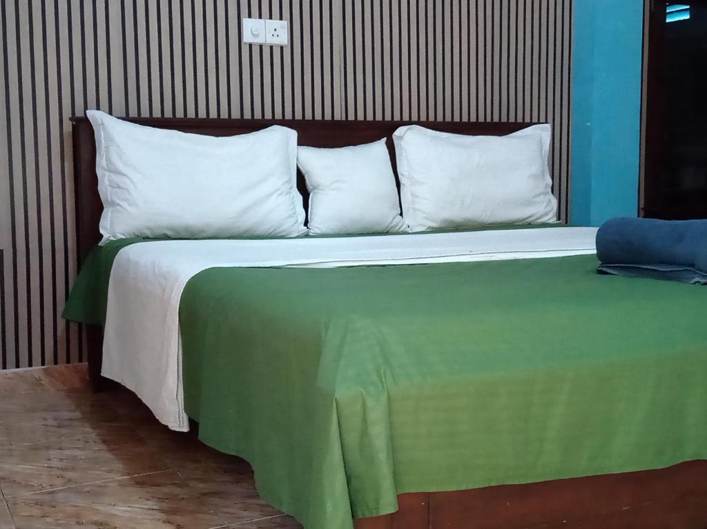 een bed met een groene deken en witte kussens bij Surf Kin Garden Inn in Weligama