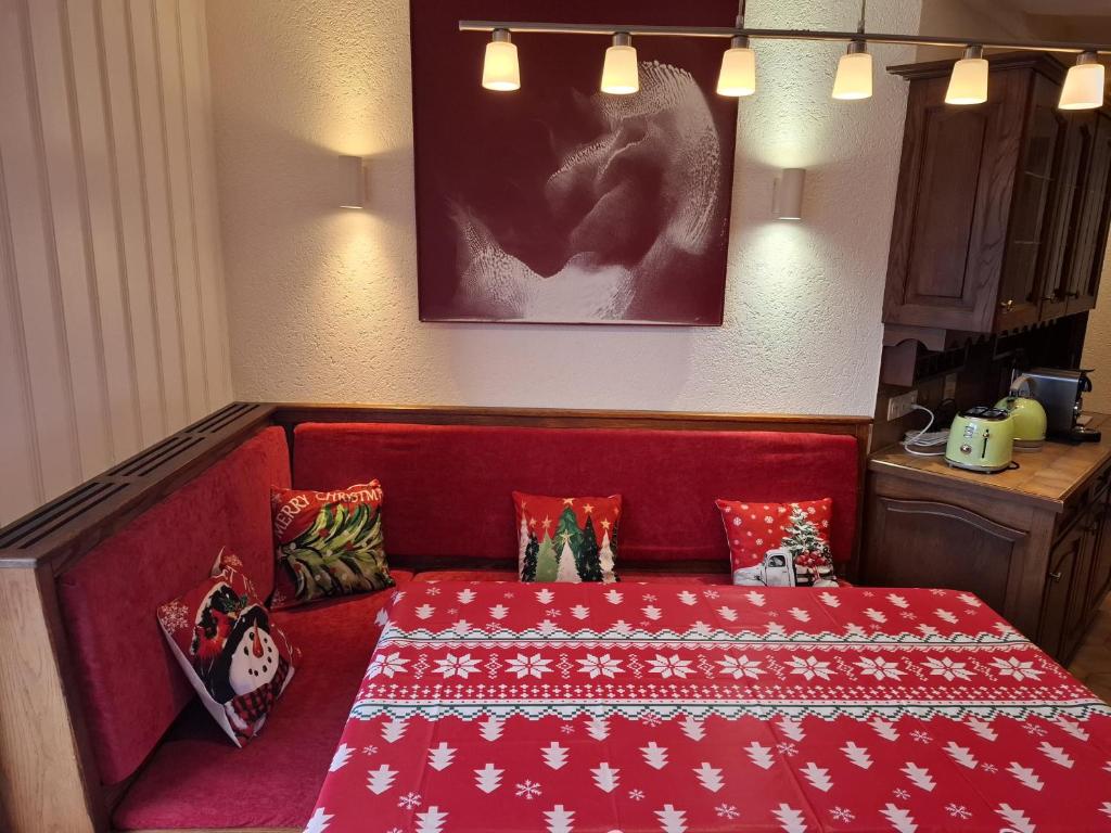 un divano rosso con cuscini in una stanza di Le Nid d'aigle apt 405 Leysin centre avec forfait piscine sauna jacuzzi en option a Leysin