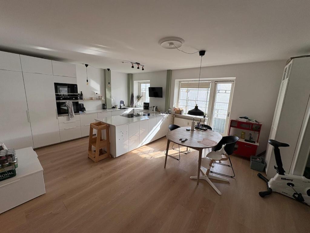 a kitchen with white cabinets and a table and chairs at 120 m2 newly renovated apartment in Copenhagen