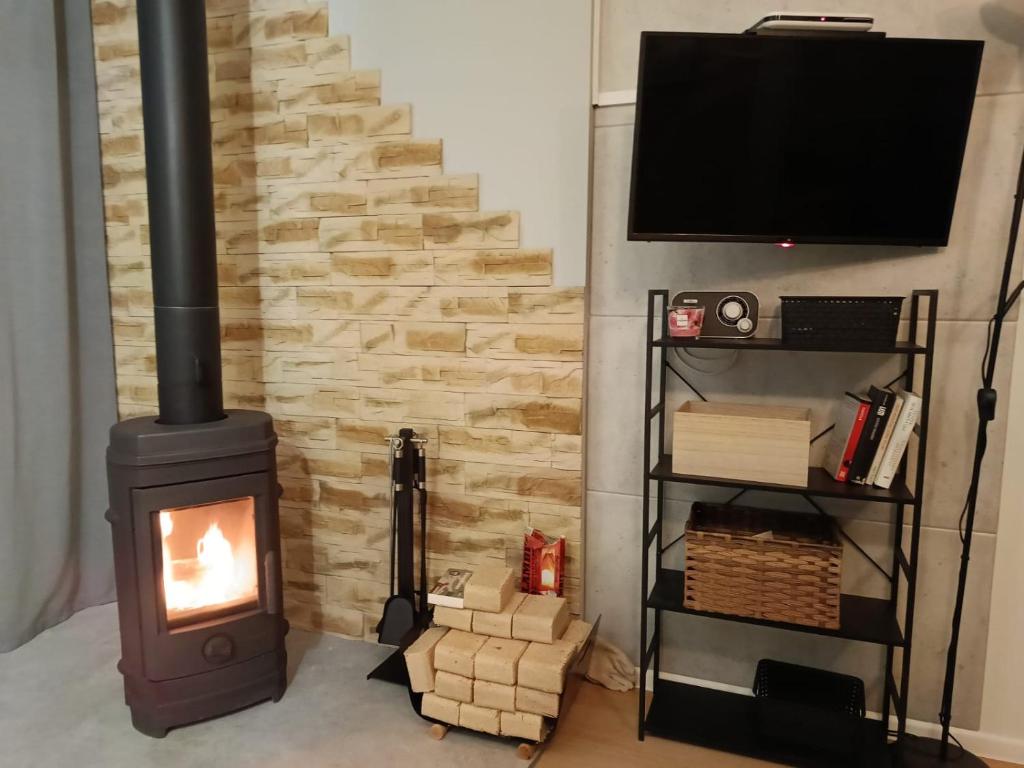 een houtkachel in een woonkamer met een tv bij Pod orzechem in Osieki