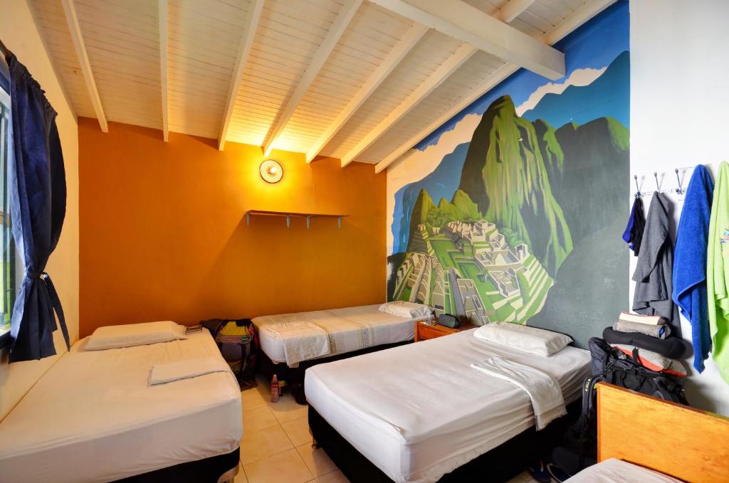 een kamer met drie bedden en een muurschildering aan de muur bij The Wandering Paisa in Medellín