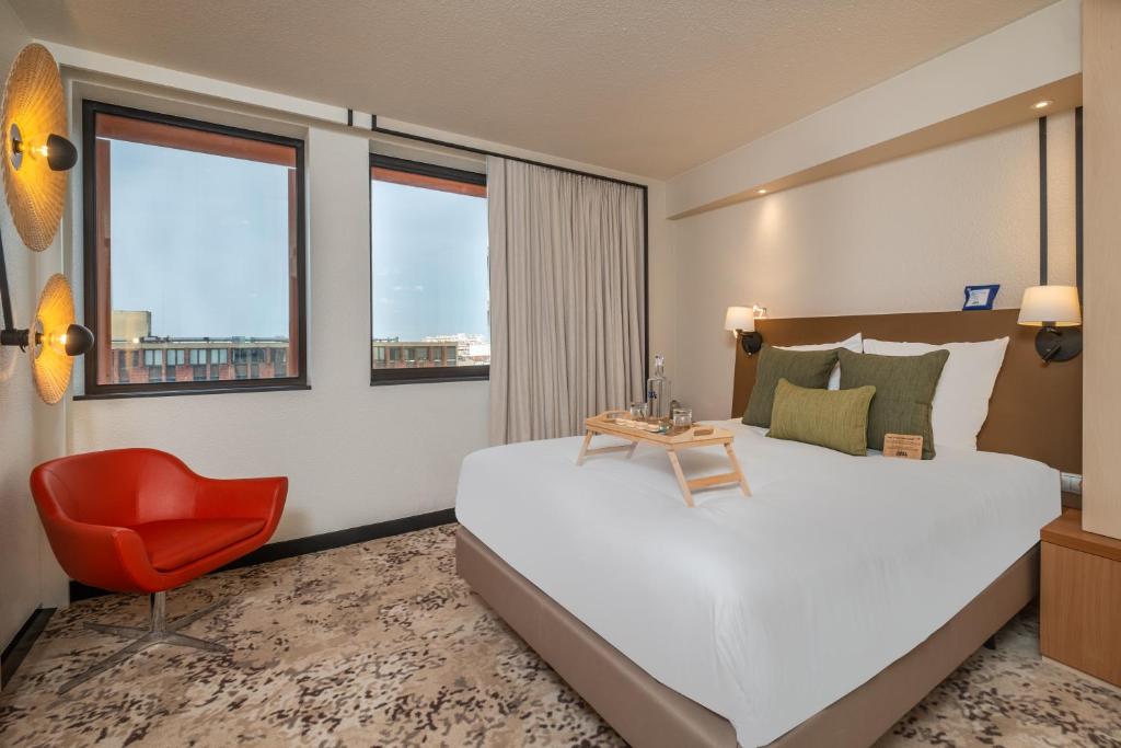 a bedroom with a large bed and a red chair at FirstName Toulouse Residence, part of JdV by Hyatt in Toulouse