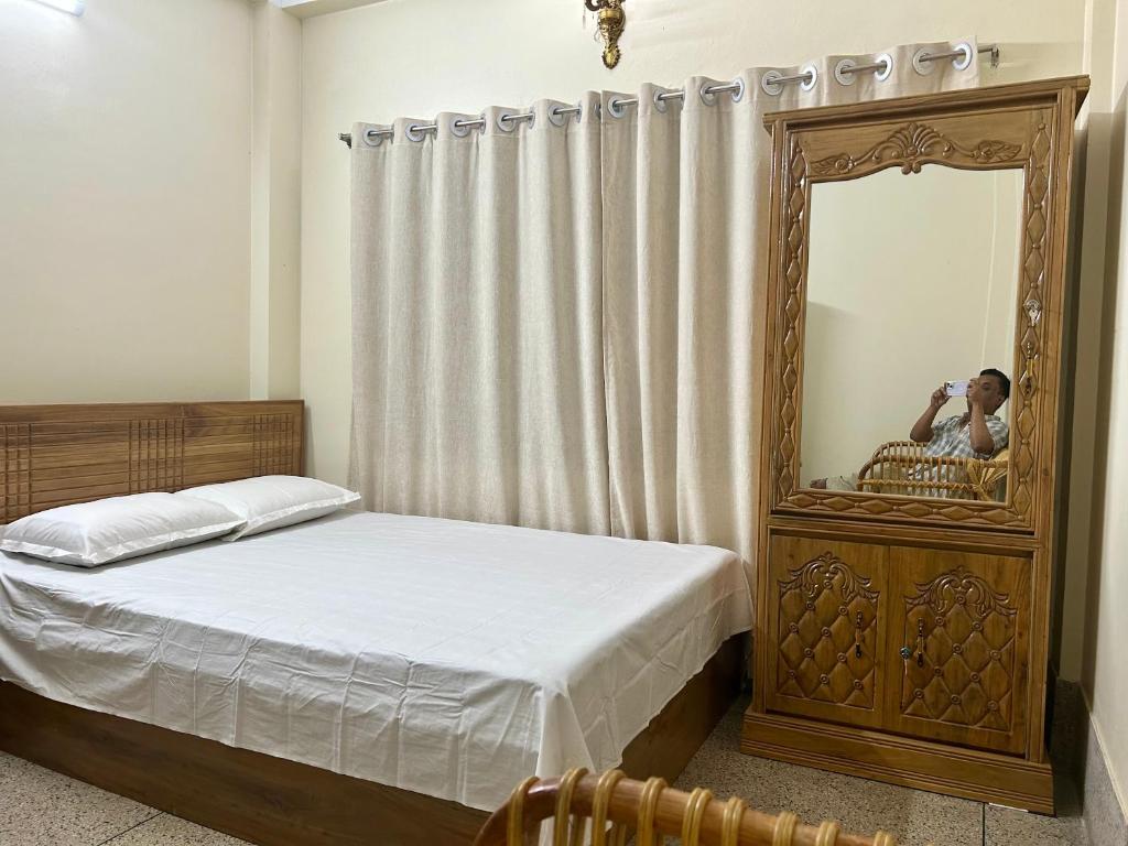 斯里曼加尔乌帕齐拉Sribhumi Homestay的一个人在卧室里用镜子照相