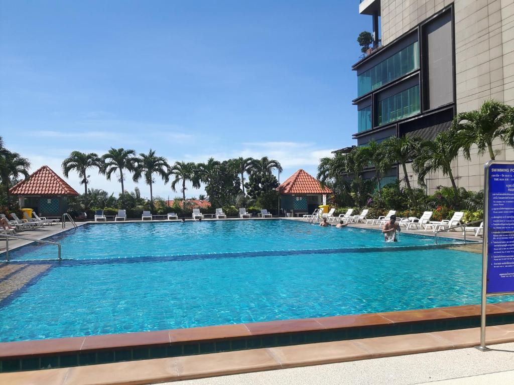 a large swimming pool with chairs and a building at View Talay6 by Blue Ocean Suite in Pattaya