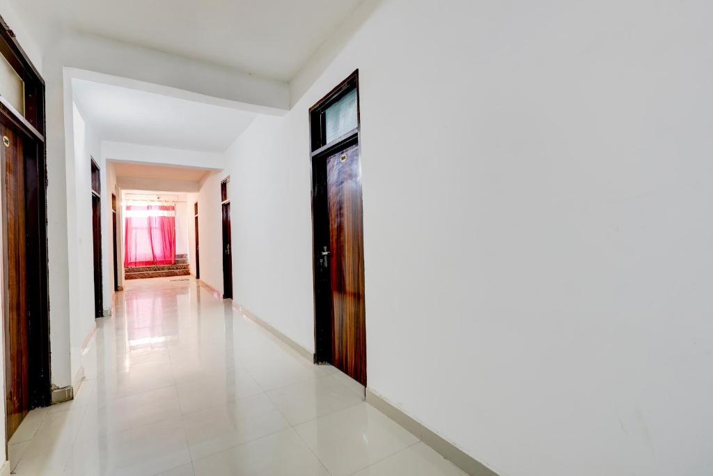 een hal met witte muren en een houten deur bij Hotel O Royal in Rewāri