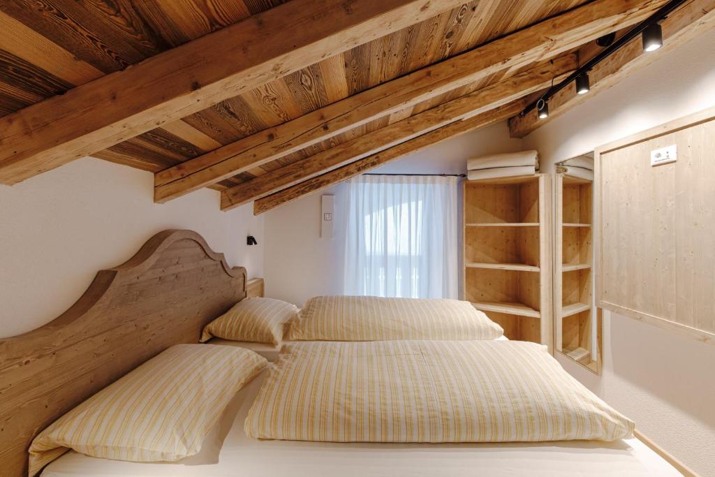 deux lits dans une chambre avec plafonds en bois dans l'établissement Appartamento Sas Ciapel, à Arabba
