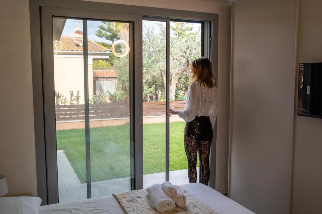 eine Frau, die aus dem Fenster eines Schlafzimmers schaut in der Unterkunft Villa Giuseppe Seaside in Lido Di Fondi