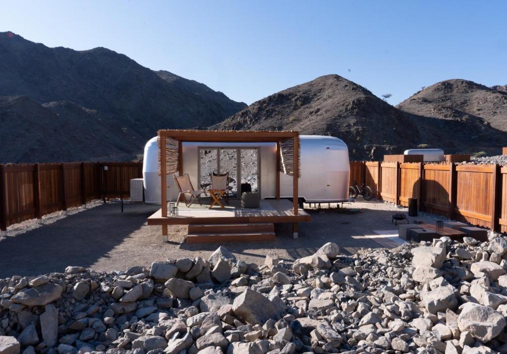 an rv parked in front of some rocks and mountains at Nomad By Sharjah Collection in Kalbā
