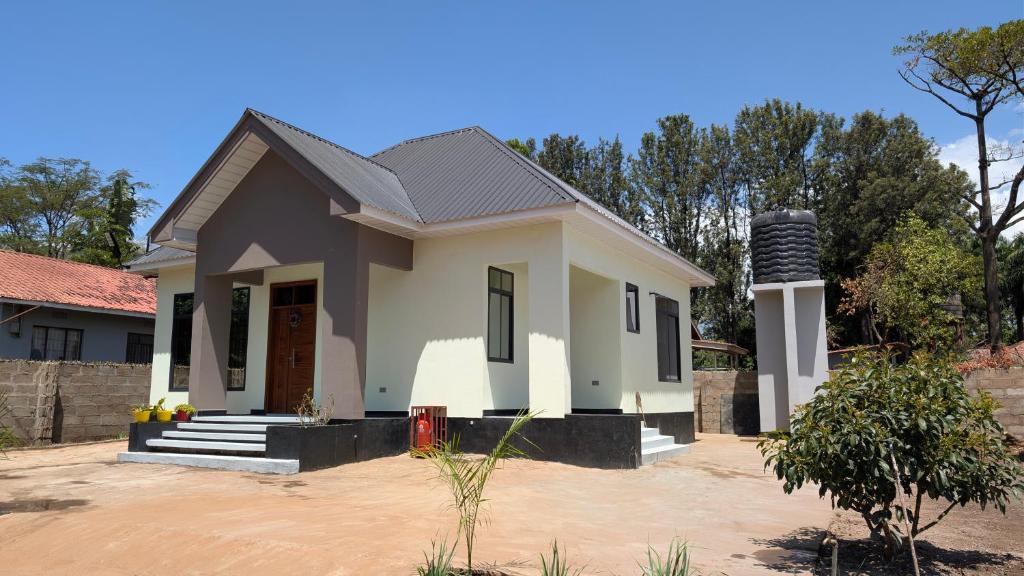 een klein wit huis in een tuin bij Danshome in Moshi