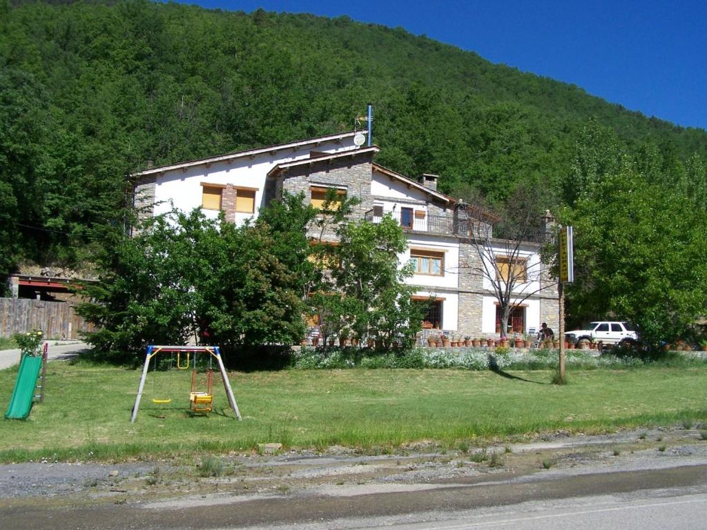 una casa vieja con un patio de juegos delante de ella en Casa la Cuadreta, en Calvera