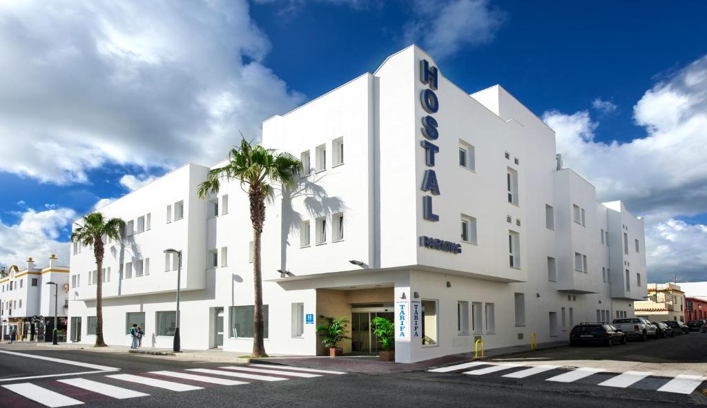 un edificio blanco en una calle con una palmera en Hostal Tarifa, en Tarifa