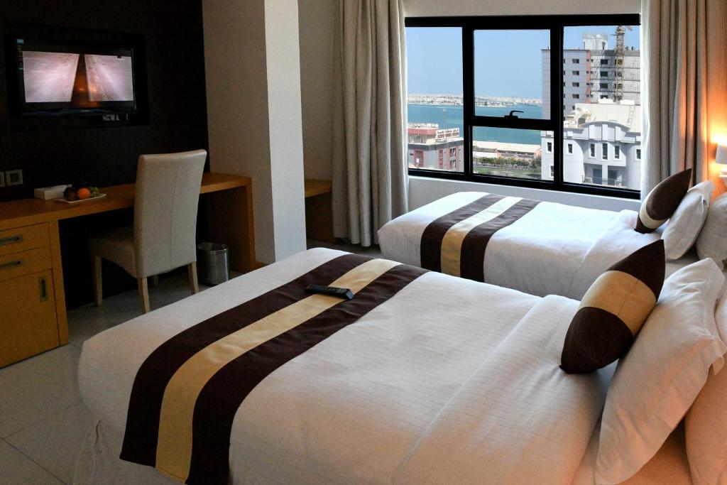 a hotel room with two beds and a large window at Al Olaya Suites Hotel in Manama