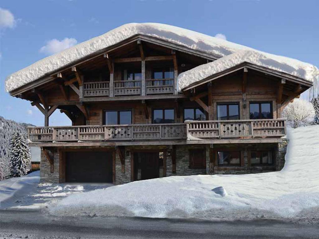 a large wooden house with a snow covered roof at Chalet de l'Atray in Les Gets