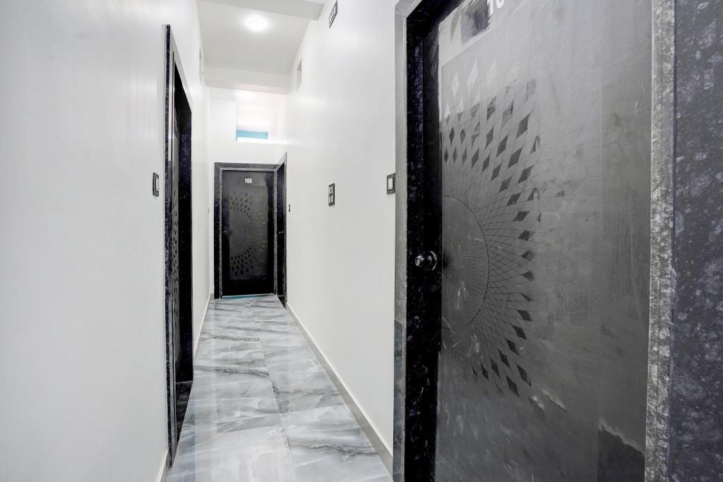 un corridoio con pareti bianche e una porta nera di SPOT ON Hotel Omava Inn a Garhā