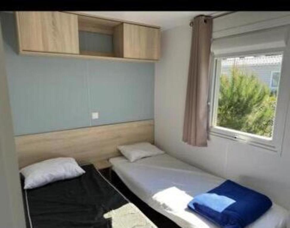 una camera da letto con due letti e una finestra di Mobil home Oasis Les Palmiers a Valras-Plage