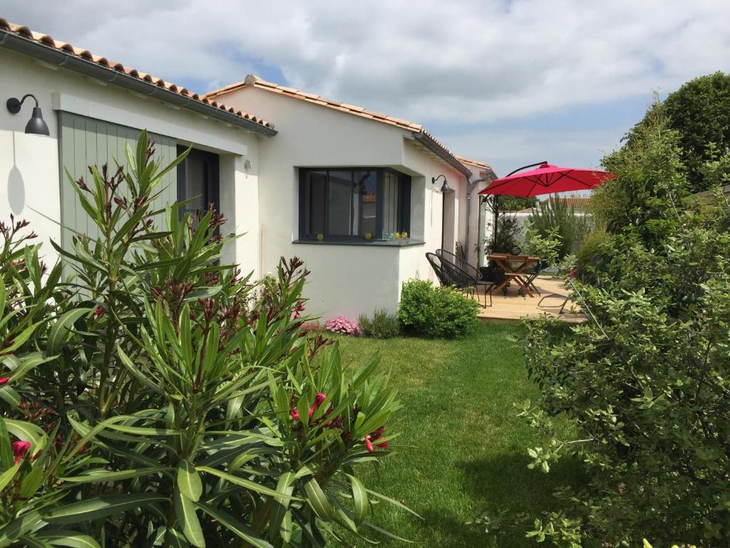 une maison avec un jardin et un parasol rouge dans l'établissement Maison d'Hôtes Les Petites Terres, à Sainte-Marie de Ré