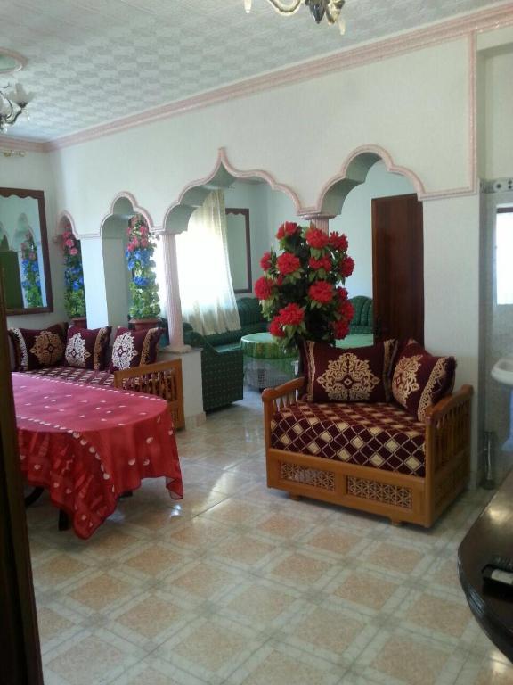 a living room with two couches and a table with flowers at Appartement bni bouayache in Aït Farts
