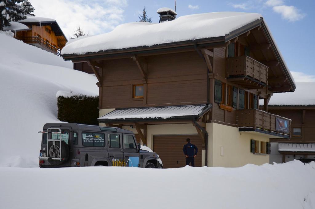 un homme debout devant une maison dans la neige dans l'établissement Chalet Le Lapye, aux Gets