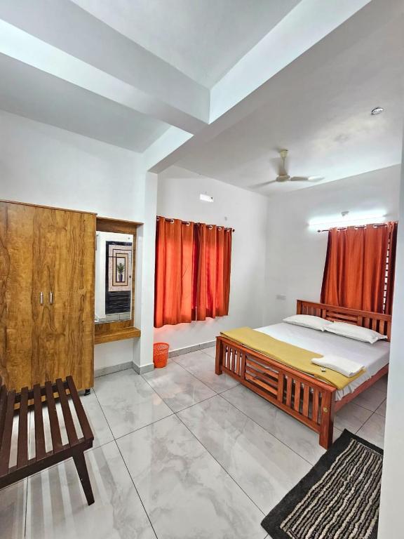a bedroom with a bed and a window with red curtains at RITHIKA HOMEs in Thekkady