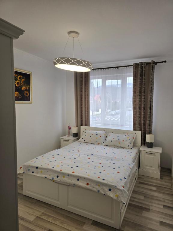 une chambre avec un lit blanc et une grande fenêtre dans l'établissement DOL House - Apartment, à Râșnov