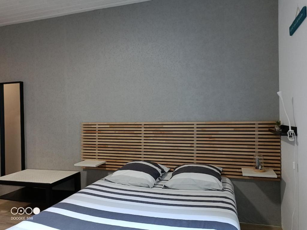 ein Schlafzimmer mit einem großen Bett mit einem hölzernen Kopfteil in der Unterkunft Studio 1 Classe 2, Fibre, Netflix in Moirans-en-Montagne