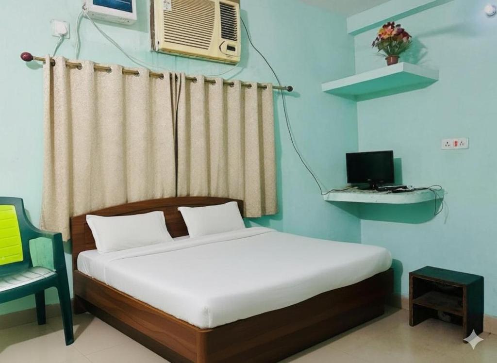 德奥加尔Alkapuri Guest House的一间卧室配有一张床、一把椅子和一台电脑