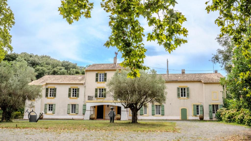 ein altes Haus mit einem Baum davor in der Unterkunft Domaine Du Castellas in Saint-Raphaël