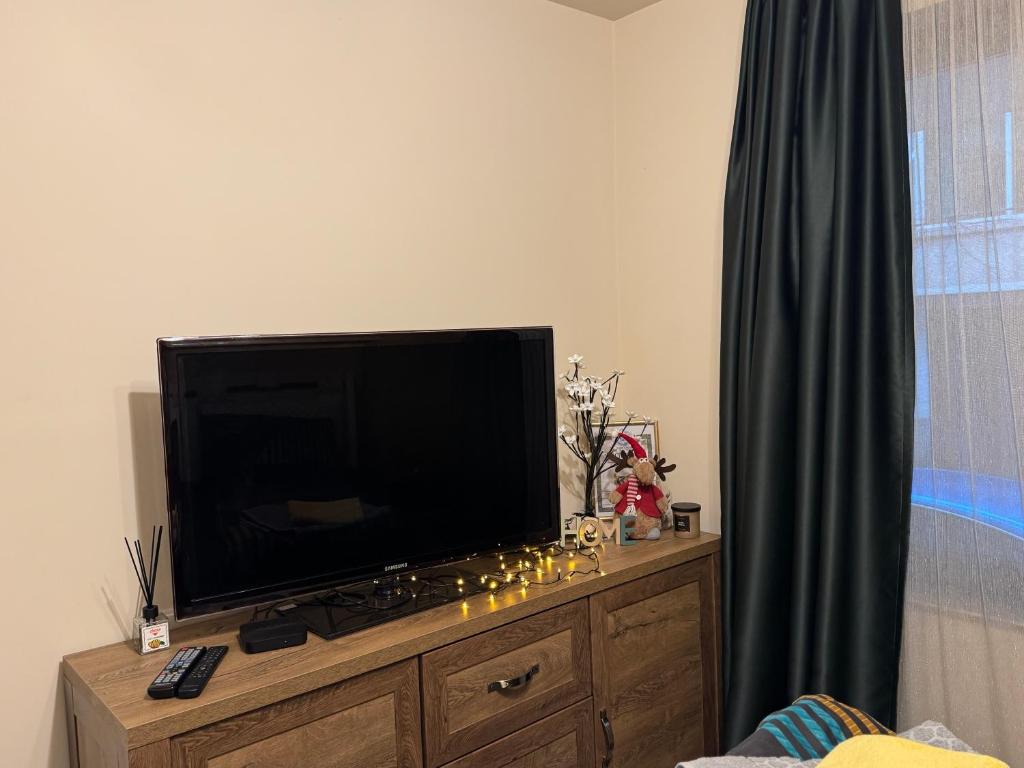 een flatscreen-tv op een houten dressoir bij Бутиков апартамент Kora DM in Stara Zagora