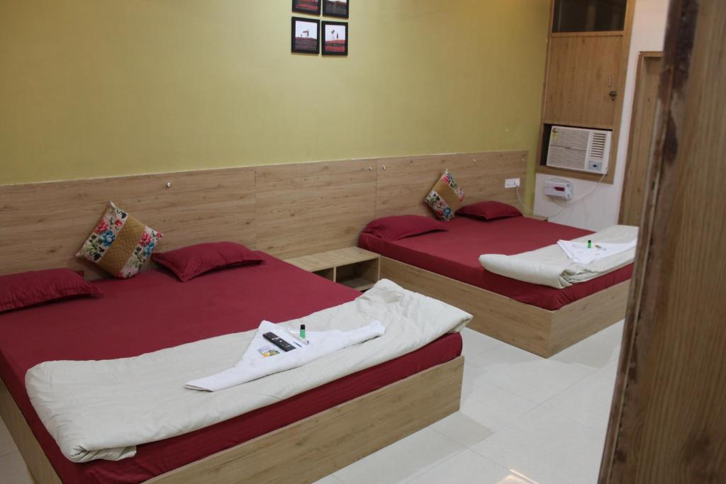 two beds in a hotel room with red sheets at Rajadhiraj Ashray- Nr Mathura Railway Station in Mathura