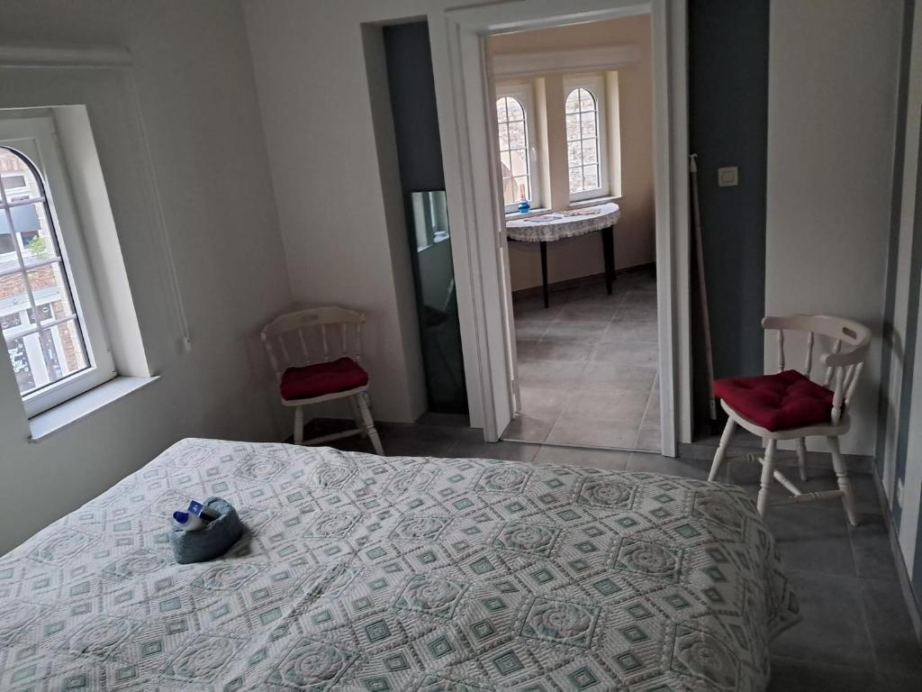 een slaapkamer met een bed en 2 stoelen en een badkamer bij Domus moerenpoort in Tongeren