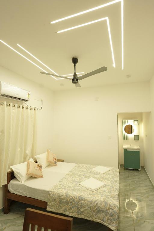 a bedroom with a bed with a ceiling fan at Mermaid Marari in Mararikulam