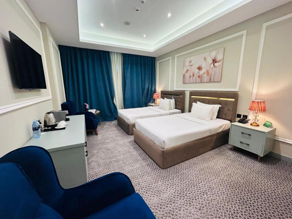 una camera d'albergo con due letti e un divano di Al Mansour Plaza Hotel a Doha