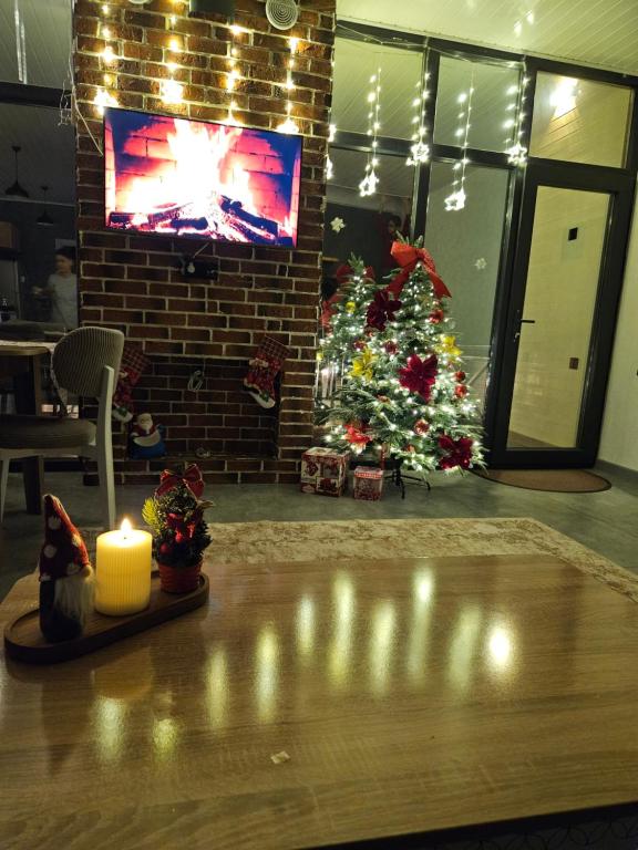 een woonkamer met een kerstboom en een kaars bij Pine Barn House in İsmayıllı