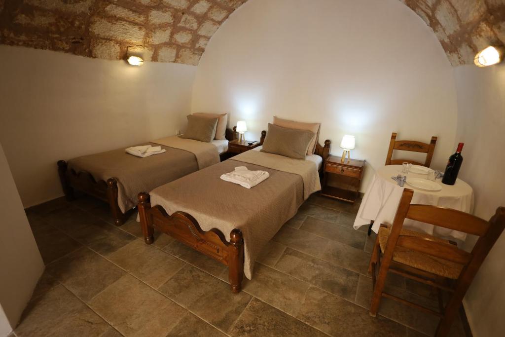 1 Schlafzimmer mit 2 Betten und einem Tisch mit einer Flasche Wein in der Unterkunft SternesVillage, Middle Ground Floor in Stérnai