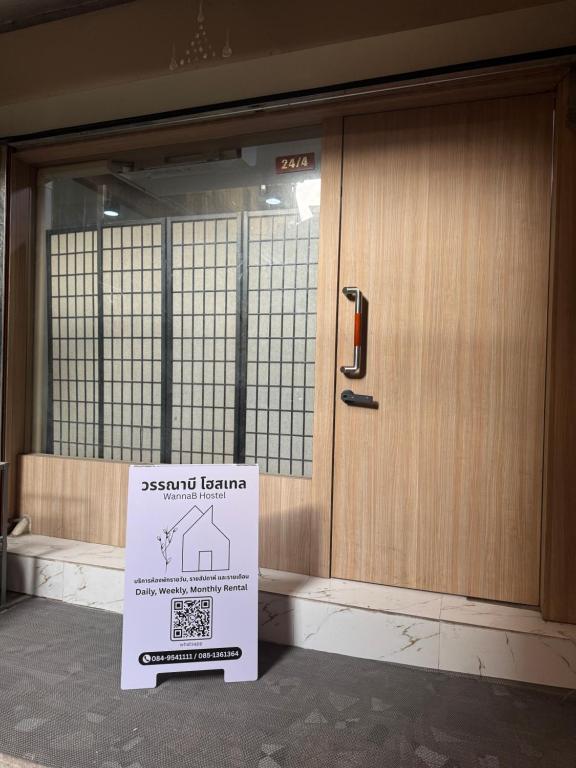 a sign is sitting in front of a door at WannaB Hostel in Khlong San