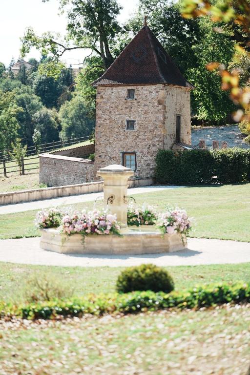 ein Steingebäude mit einem Brunnen in einem Park in der Unterkunft Château de Laforest - Les Tours in Thizy-les-Bourgs