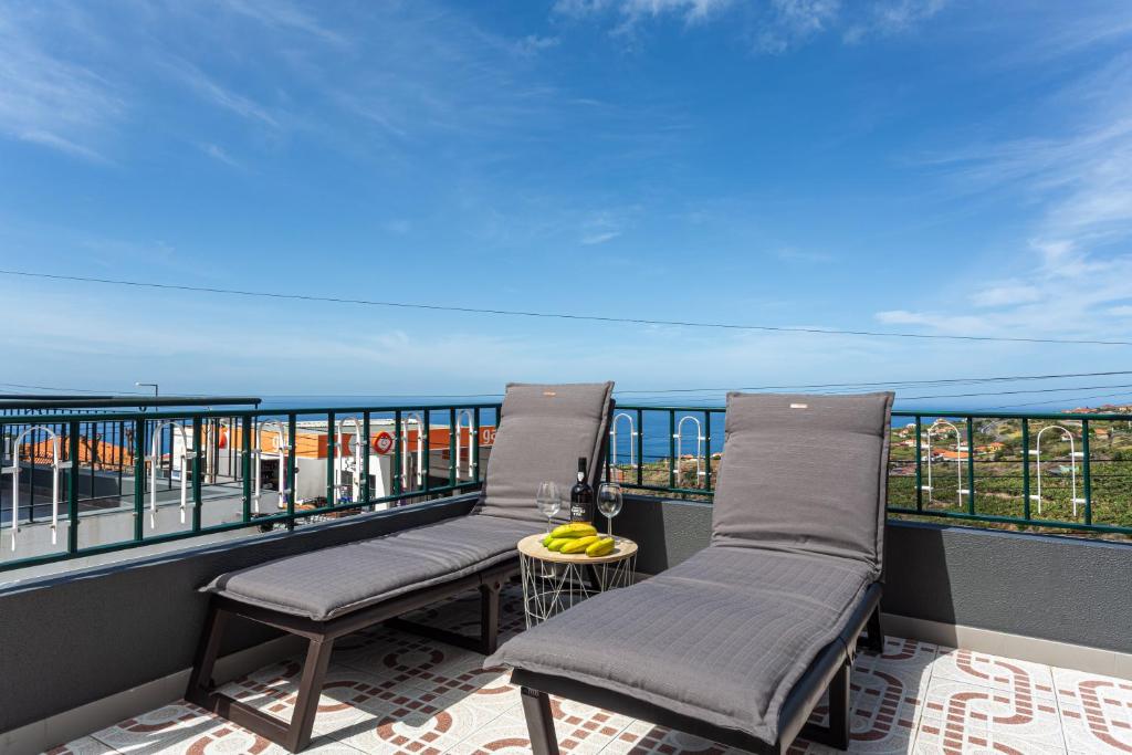 a balcony with two chairs and a table with bananas on it at Estrela House I Calheta Madeira in Calheta