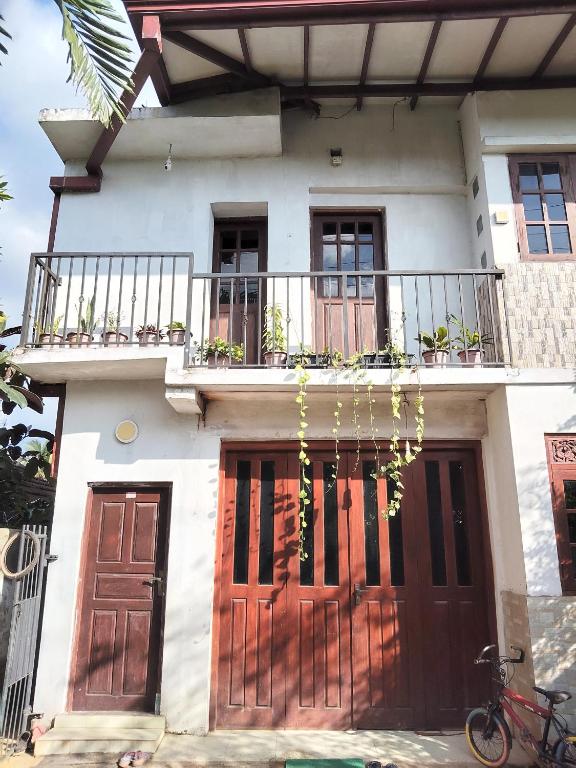 a white house with brown doors and a balcony at Foreign Home Stay in Katugastota
