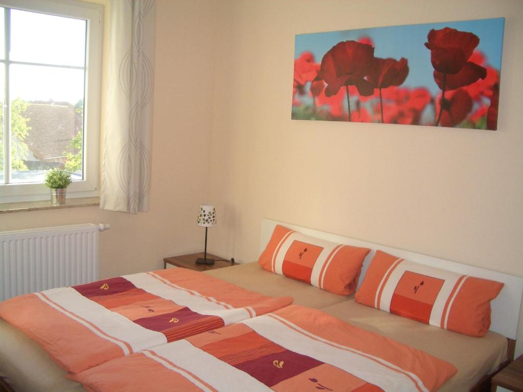 Schlafzimmer mit einem Bett mit orangefarbenen und weißen Kissen in der Unterkunft Ferienwohnung Rerik in Rerik