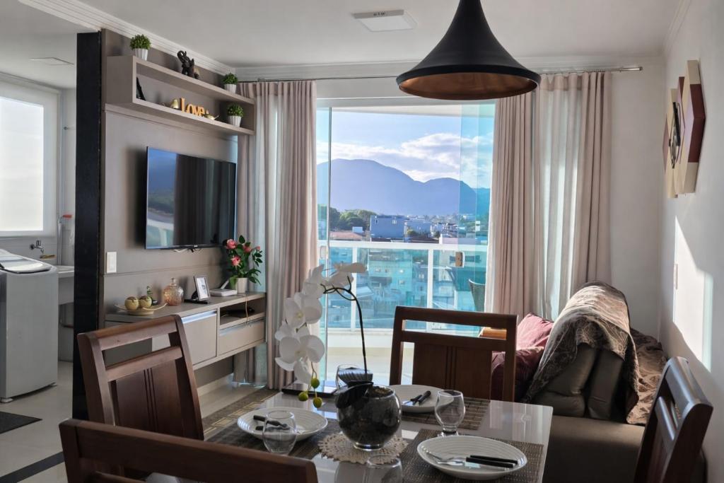 a living room with a table and a large window at Vista para as Montanhas in Guarapari