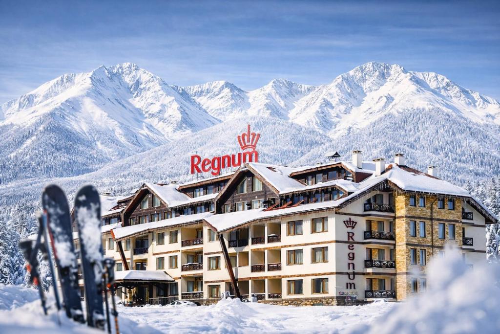 un hôtel sous la neige, au pied des montagnes dans l'établissement Regnum Bansko Ski Hotel & SPA, à Bansko
