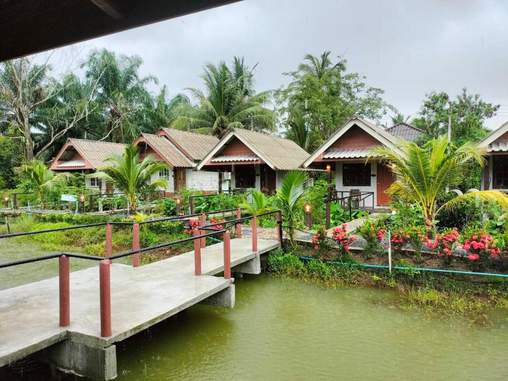 a row of houses with a bridge over a river at ปารมีฟาร์มสเตย์ in Ban Chao Nam