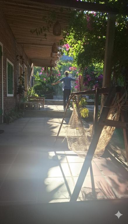 绥和市Homestay Dat Phu的一个女人扛着吊床走下门廊。