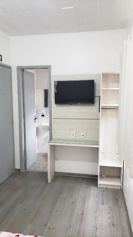 een kamer met een bureau en een televisie. bij Hotel leo in Pelotas